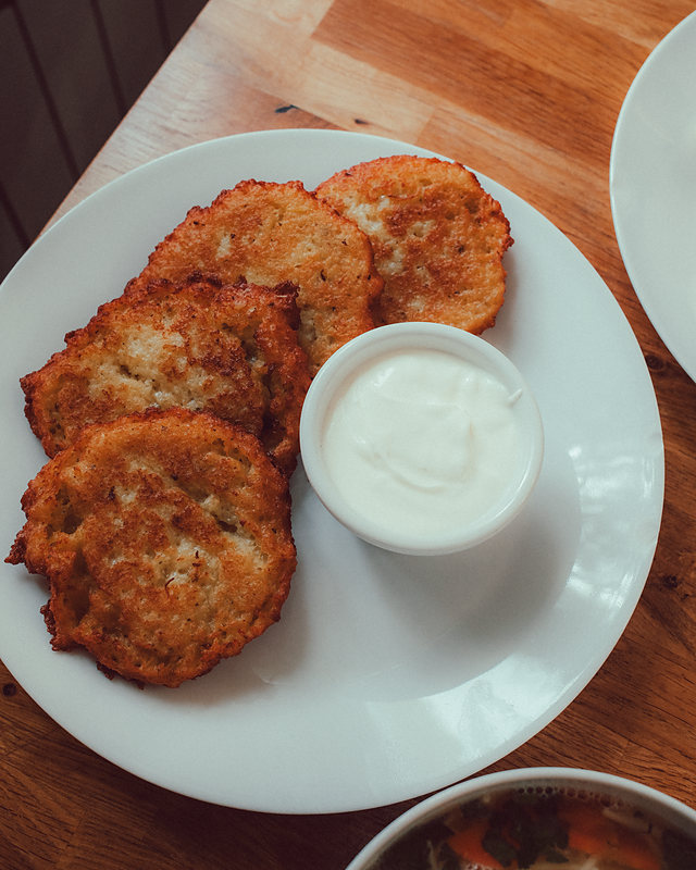 Golden potato pancakes on a plate with sour cream
