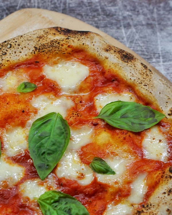 Wood-fired margherita pizza with charred crust and fresh basil