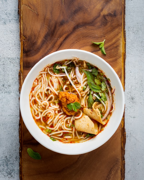 Spicy noodle soup with herbs, red onion and chili broth