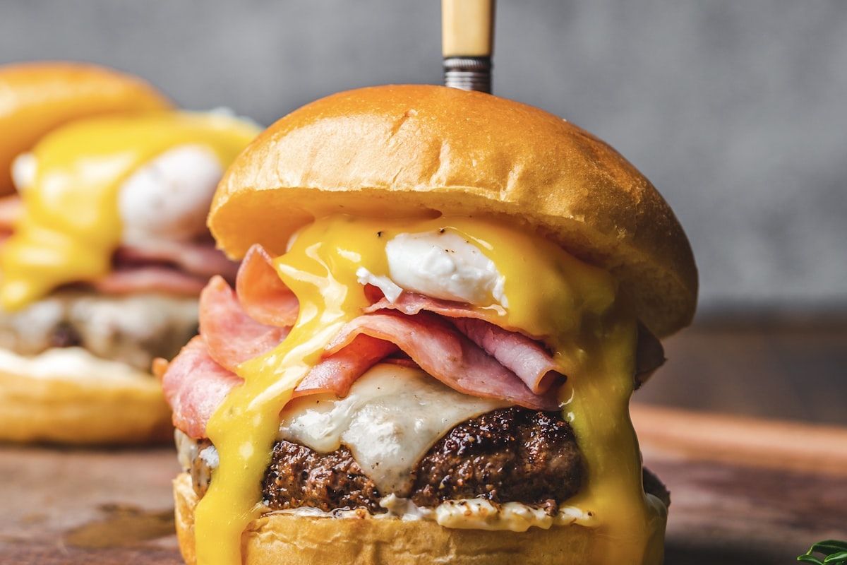 Brioche burger stacked with beef patty, ham, poached egg and hollandaise sauce