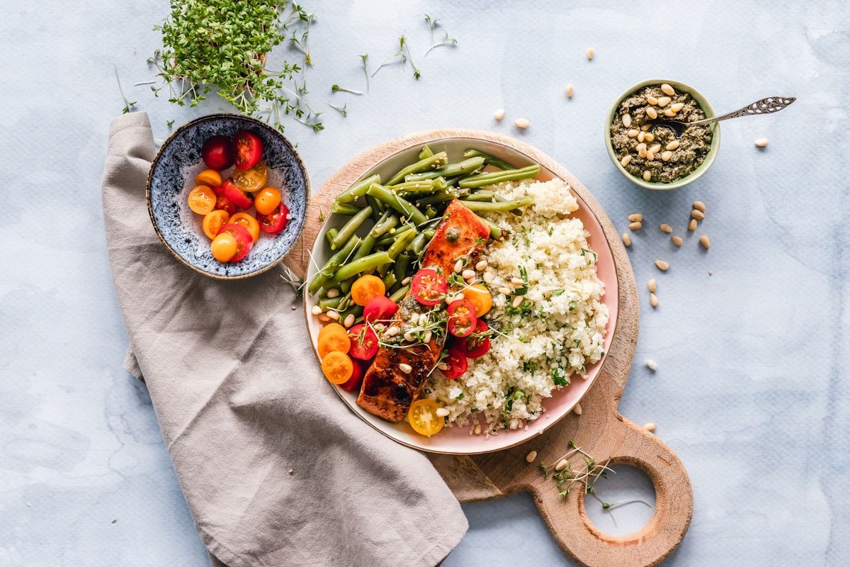 Bowl of herbed couscous with glazed salmon, green beans, cherry tomatoes and pine nuts